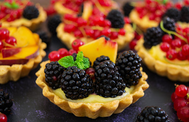 Tartlets with different berries on dark background