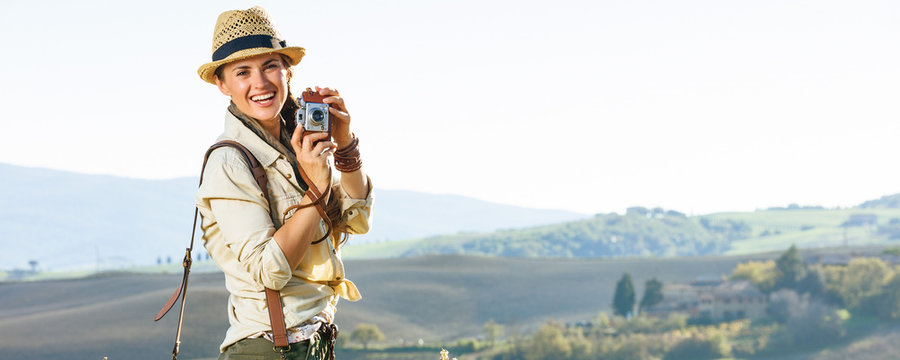 smiling woman hiker hiking in Tuscany with retro photo camera