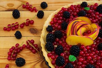 Delicious tart with red currants, peach and blackberries