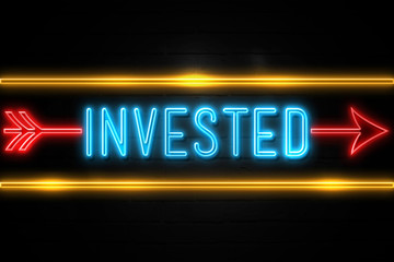 Invested  - fluorescent Neon Sign on brickwall Front view
