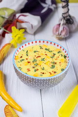 Homemade corn cream soup with thyme and pepper chili on a gray background