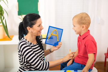 Little boy during lesson with his speech therapist. Learning through fun and play