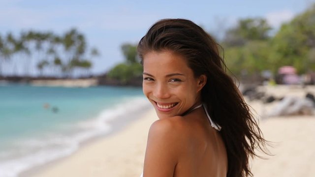 Portrait of happy woman standing at beach. Beautiful young female is on summer vacation. She is enjoying on sunny day. Beautiful mixed race Asian Chinese / Caucasian girl.