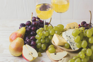 Cheese plate served with wine, fresh grapes and pears
