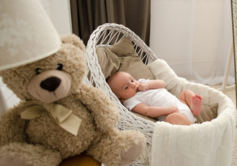 Baby newborn lies in the cradle. Toy bear