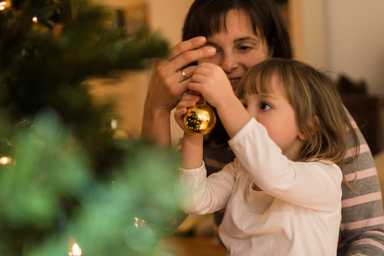 Mother helping daughter to decorate xmas tree