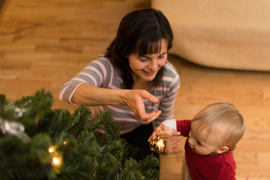 Toddler with mom decorating christmas tree
