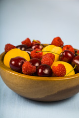 Ripe berries in a plate on a wooden table.
