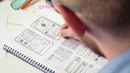 UX designer sketching prototype of a new app in his notebook