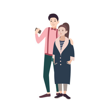 Young fashionable couple of man and woman dressed in stylish clothes embracing and making selfie on smartphone