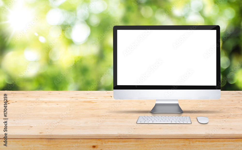 Aufkleber Blank screen desktop computer on wooden table top with blur green tree in garden bokeh background,Mock up for display or montage of design