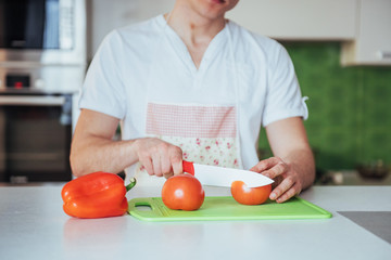 man cuts vegetables together in the kitchen