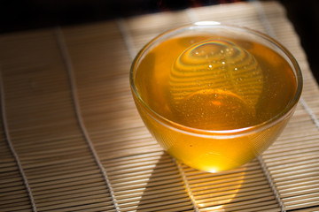 deep saucer of honey on the table, illuminated by the sun