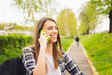 Fototapeta premium Happy teenage student girl talking on the phone outdoors