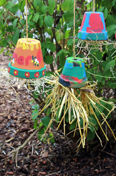 three colorful flower pots filled with straw hanging upside-down