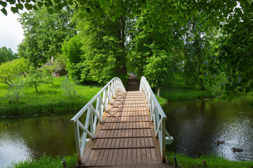 White wooden bridge in the old park in the village of Mikhailovskoye, Pskov region, Russia