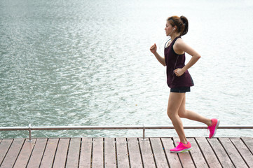 Asian sport woman jogging on lake rim in park for health