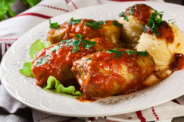 Stuffed cabbage with meat and rice served with boiled potatoes and tomato sauce