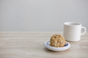 WHITE COFFEE CUP AND COOKIESWhite coffee cup with cookies on the wood table. 
