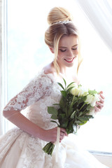 Young beautiful bride. Wedding hairstyle, blond hair, wedding dress, makeup and bride's bouquet.