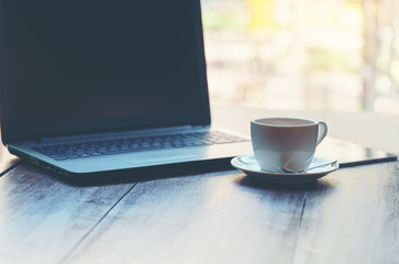 Hot cup of tea and laptop on wood table