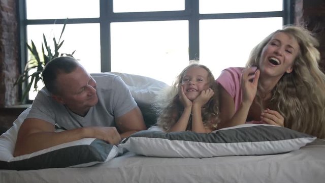 Portrait of family with daughter posing in bed