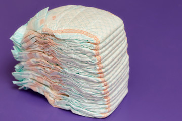 Stack of diapers or nappies on purple background