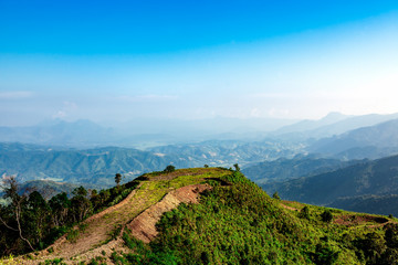 A landscape of green hills with Blue mountains and valley 