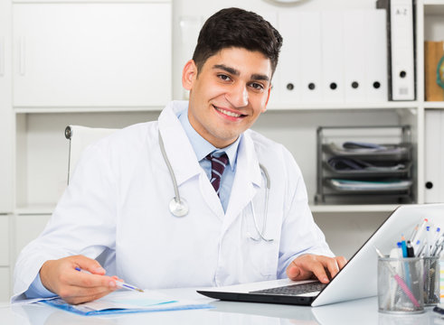 Young smiling doctor is doing report about patients
