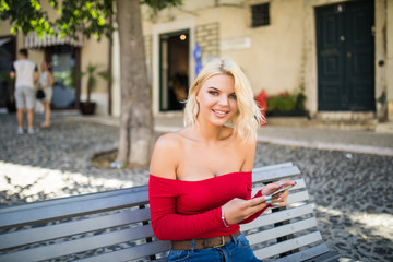 Young woman blonde girl summer portrait with mobile phone in the city streets