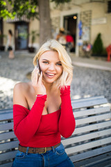 Fototapeta premium Lovely blond smile girl sitting on a bench and talking on the phone.