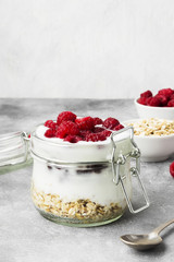 Glanola in glass jar with raspberry on a gray background