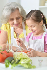 Grandmother and granddaughter stirring salad