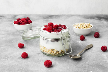 Glanola in glass jar with raspberry on a gray background