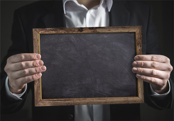 Businessman holding in hand an empty blackboard with frame