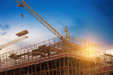 Construction site, silhouettes of construction industry workers on scaffolding against the sunset...