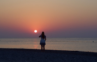 Junge Frau blickt dem Sonnenaufgang entgegen