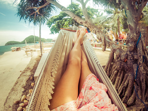 Legs Of Woman Relaxing In Hammock On A Tropical Beach