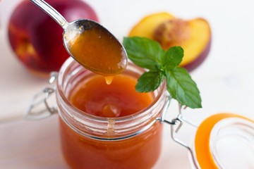 Peach jam served by teaspoon from glass jar