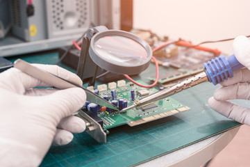 The abstract image of asian technician repairing the computer mainboard by soldering in the lab....