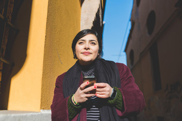 Portrait of young woman looking over smiling, holding smart phone - technology, happiness, different beauty concept
