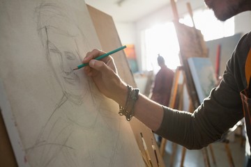 Cropped image of man sketching on canvas