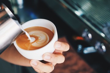 Barista pouring milk for making coffee latte art.