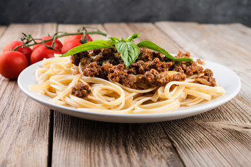 Italian spaghetti   with bolognese sauce, meat, cheese and fresh tomatoes and  basil - homemade healthy italian pasta on rustic wooden background.