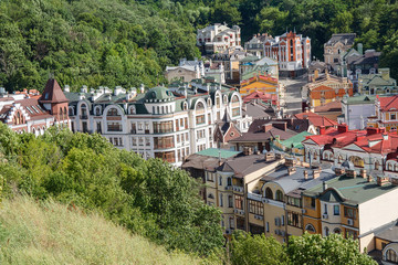 Fototapeta na wymiar Multicolored houses surrounded by green trees. Kiev, Ukraine