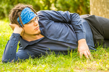 young man laying on the grass in a park