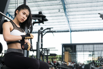 Fototapeta na wymiar young woman wearing gloves in fitness center. female athlete prepare for training in gym. sporty girl ready for working out in health club.