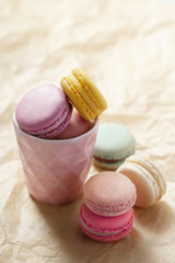 Colorful macarons on a brown background. French sweets assortment viewed from above on a neutral paper background