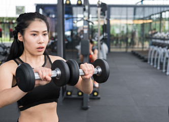 Fototapeta na wymiar young woman execute exercise in fitness center. female athlete lift dumbbell in gym. sporty girl working out in health club.