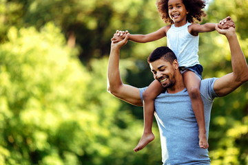 Portrait of young father carrying his daughter on his back